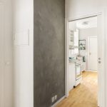 Spacious and bright modern apartment hallway featuring white walls and wooden floors.